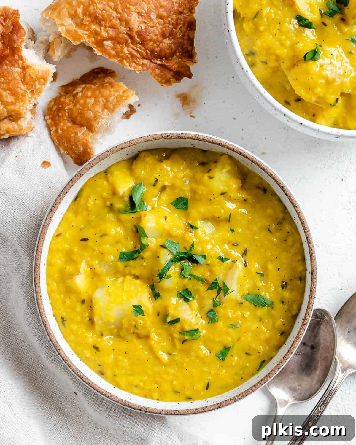 30 Effortless Plant-Based Potato Creations 7 completed Lentil Potato Soup in a white bowl with ingredients in the background