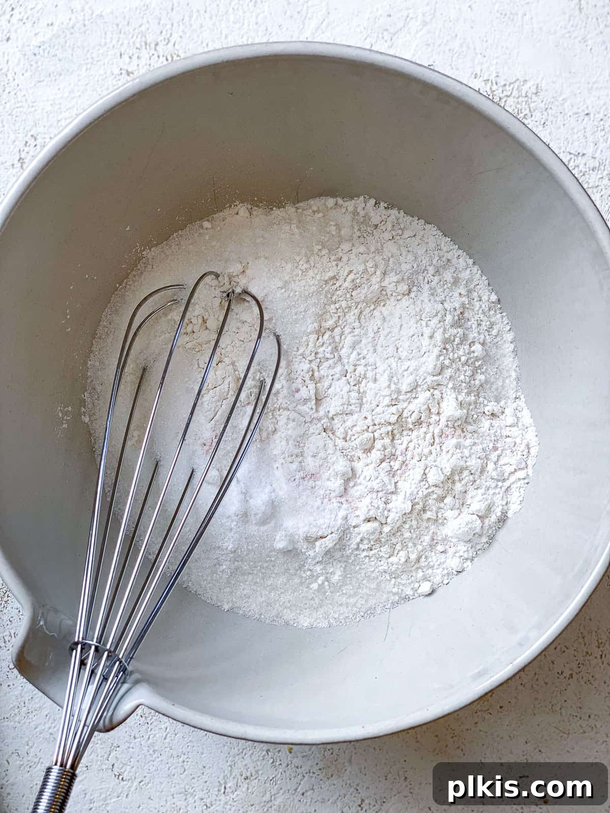 Wholesome Vegan Zucchini Muffins 6 A process shot showing ingredients being whisked together in a large bowl, demonstrating the combination of wet and dry elements for the muffin batter.
