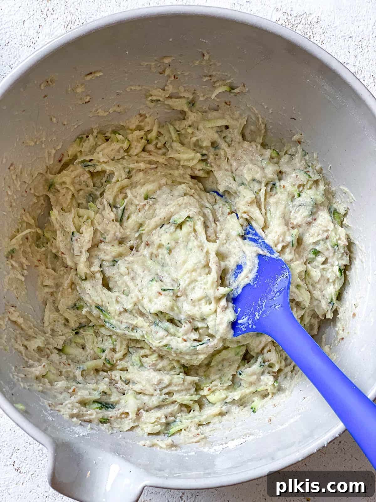 Wholesome Vegan Zucchini Muffins 7 A process shot illustrating the gentle mixing of ingredients in a bowl to form the vegan zucchini muffin batter.