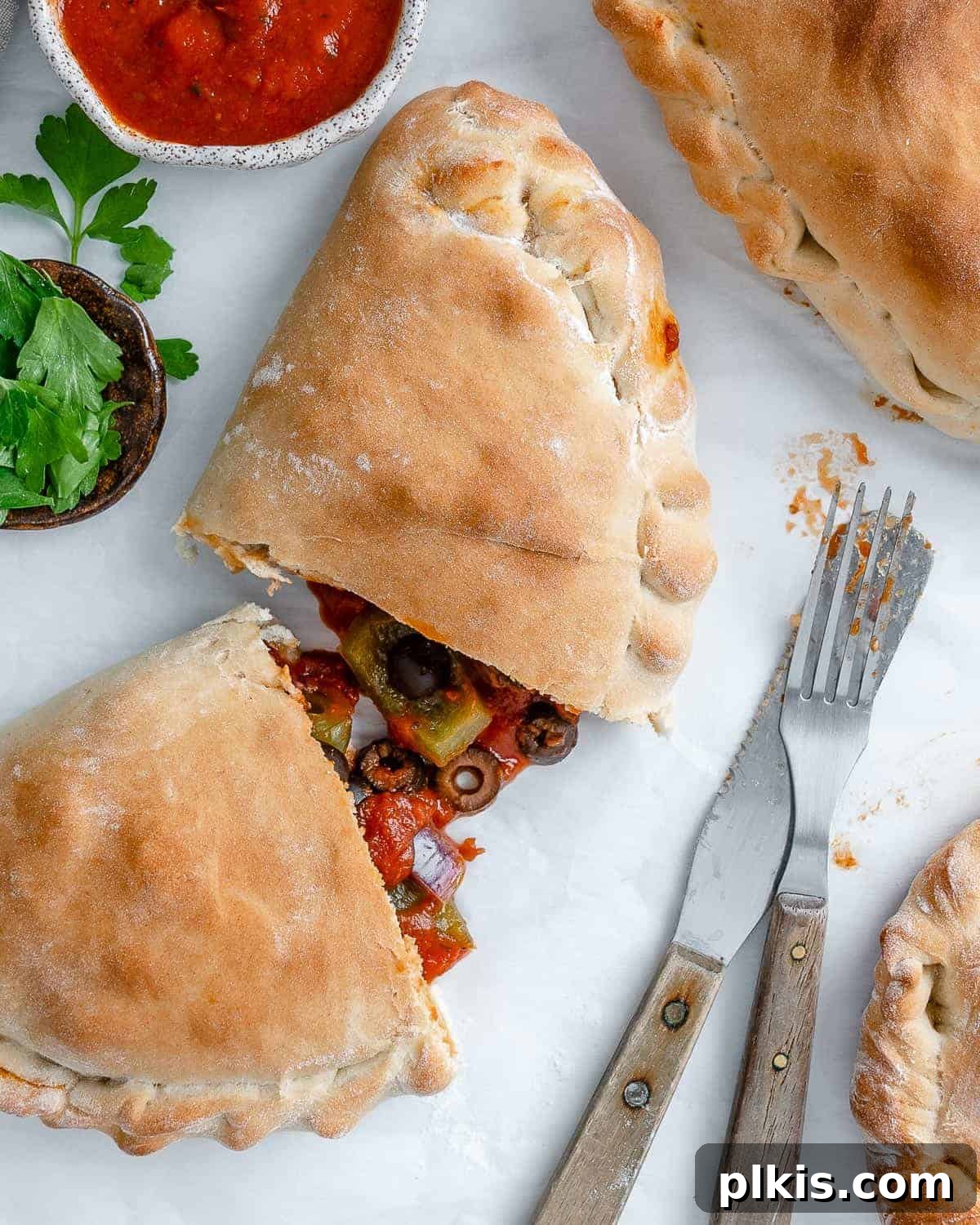 Perfect Vegan Calzones with Homemade Pizza Dough 19 completed Marinara Calzone split open in the middle against white surface