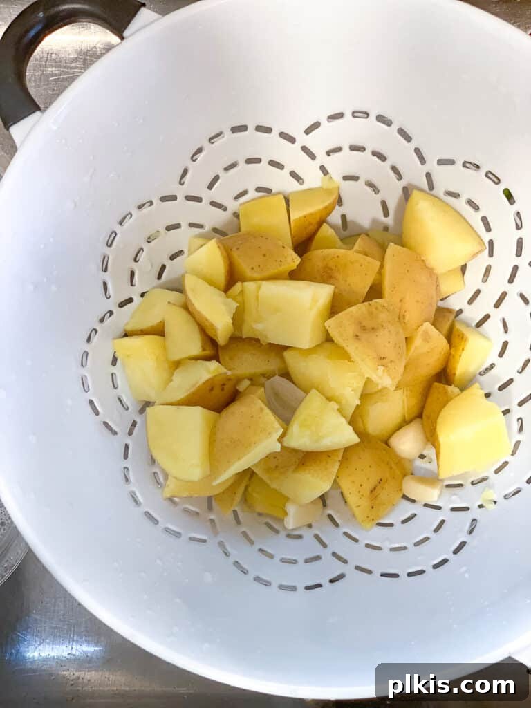 Wholesome Lentil Shepherd's Comfort 14 Cooked potatoes and garlic being drained in a colander after boiling.