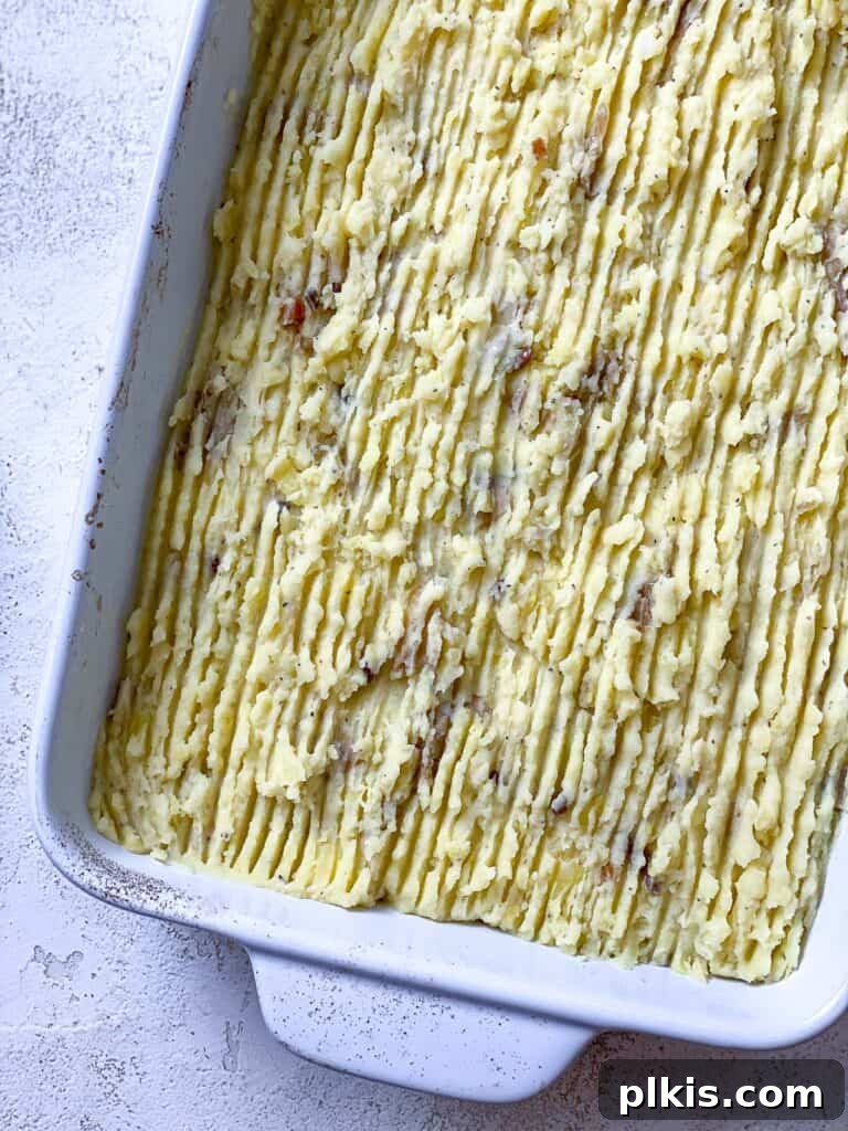 Wholesome Lentil Shepherd's Comfort 20 Creamy mashed potatoes spread over the lentil filling in a casserole dish, ready for baking.