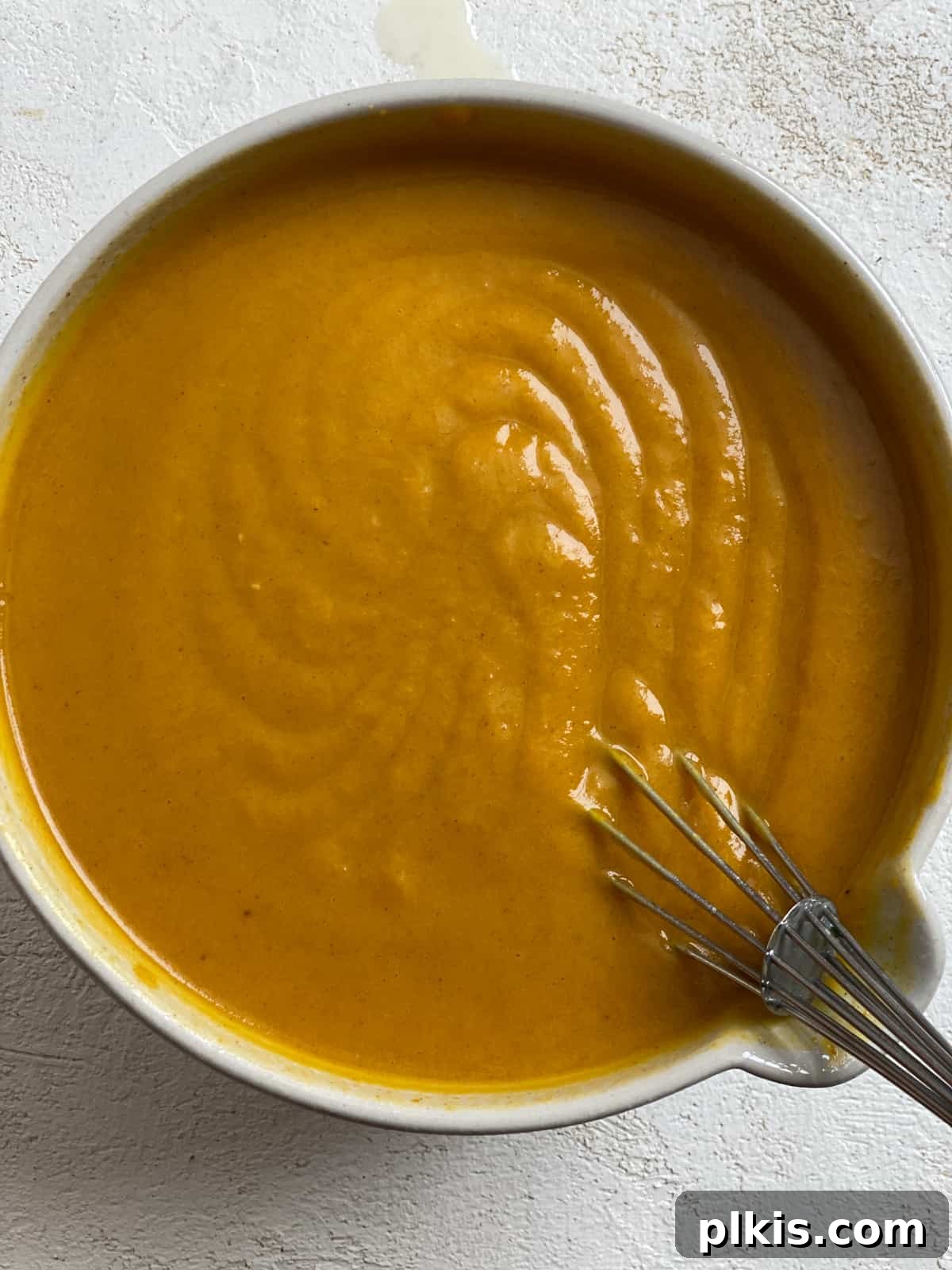 Effortless Vegan Pumpkin Perfection 4 A large bowl containing the rich, orange vegan pumpkin pie filling mixture, being whisked to a smooth consistency.