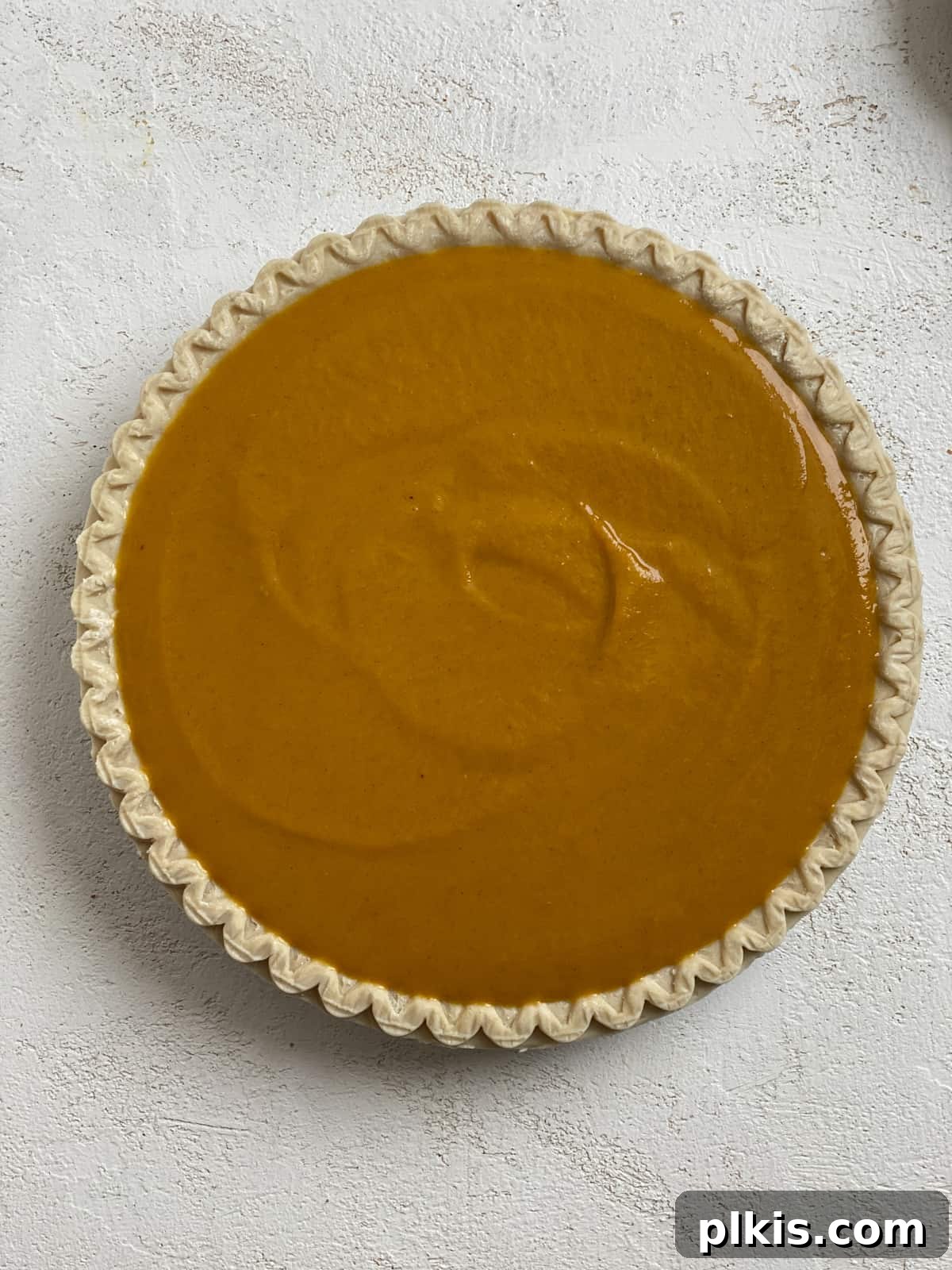 Effortless Vegan Pumpkin Perfection 5 An unbaked Easy Vegan Pumpkin Pie with its smooth, vibrant filling nestled in a golden crust, ready for the oven.