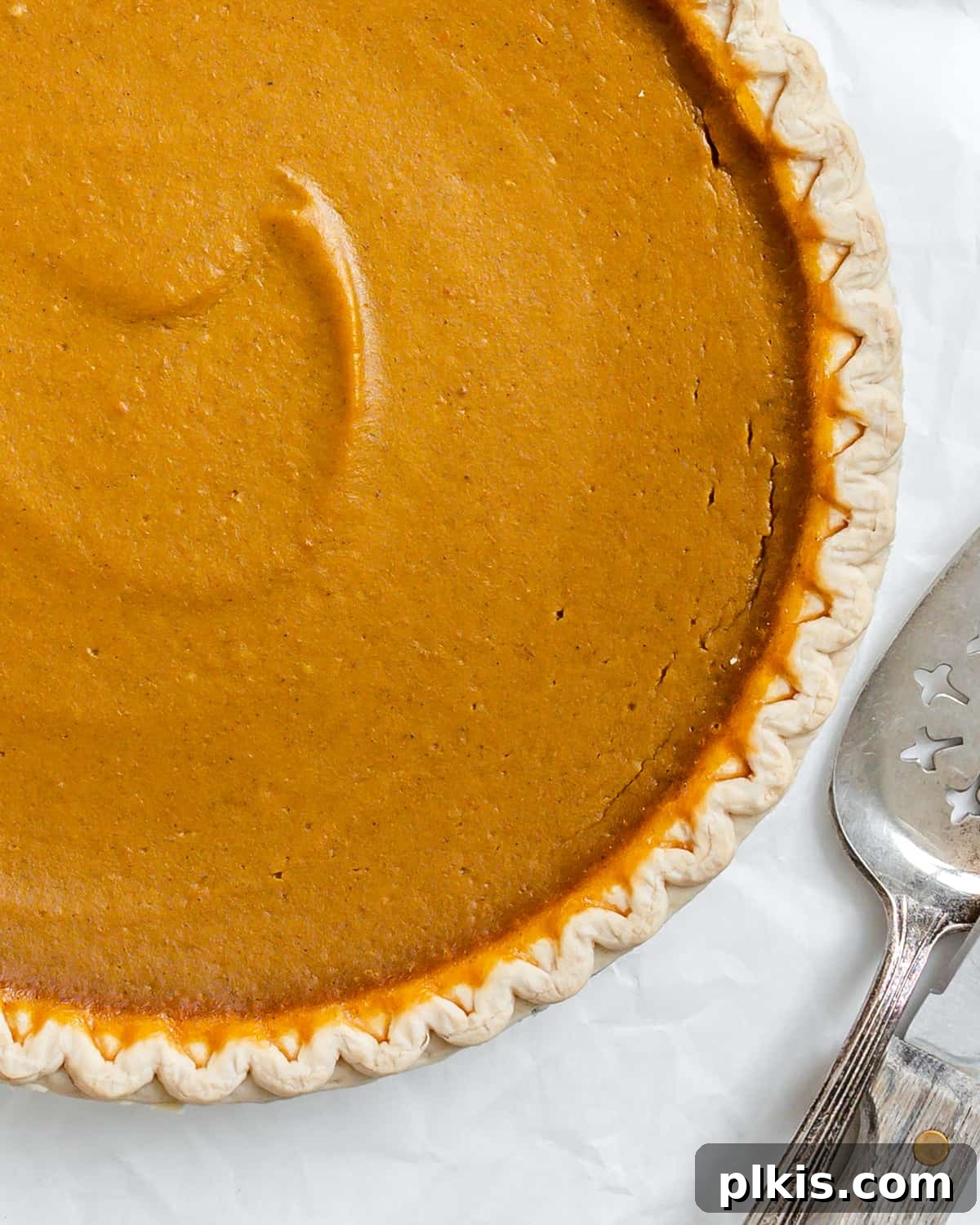 Effortless Vegan Pumpkin Perfection 6 A perfectly baked and cooled Easy Vegan Pumpkin Pie, showcasing its smooth texture and golden crust, presented against a clean white background, ready to be served.