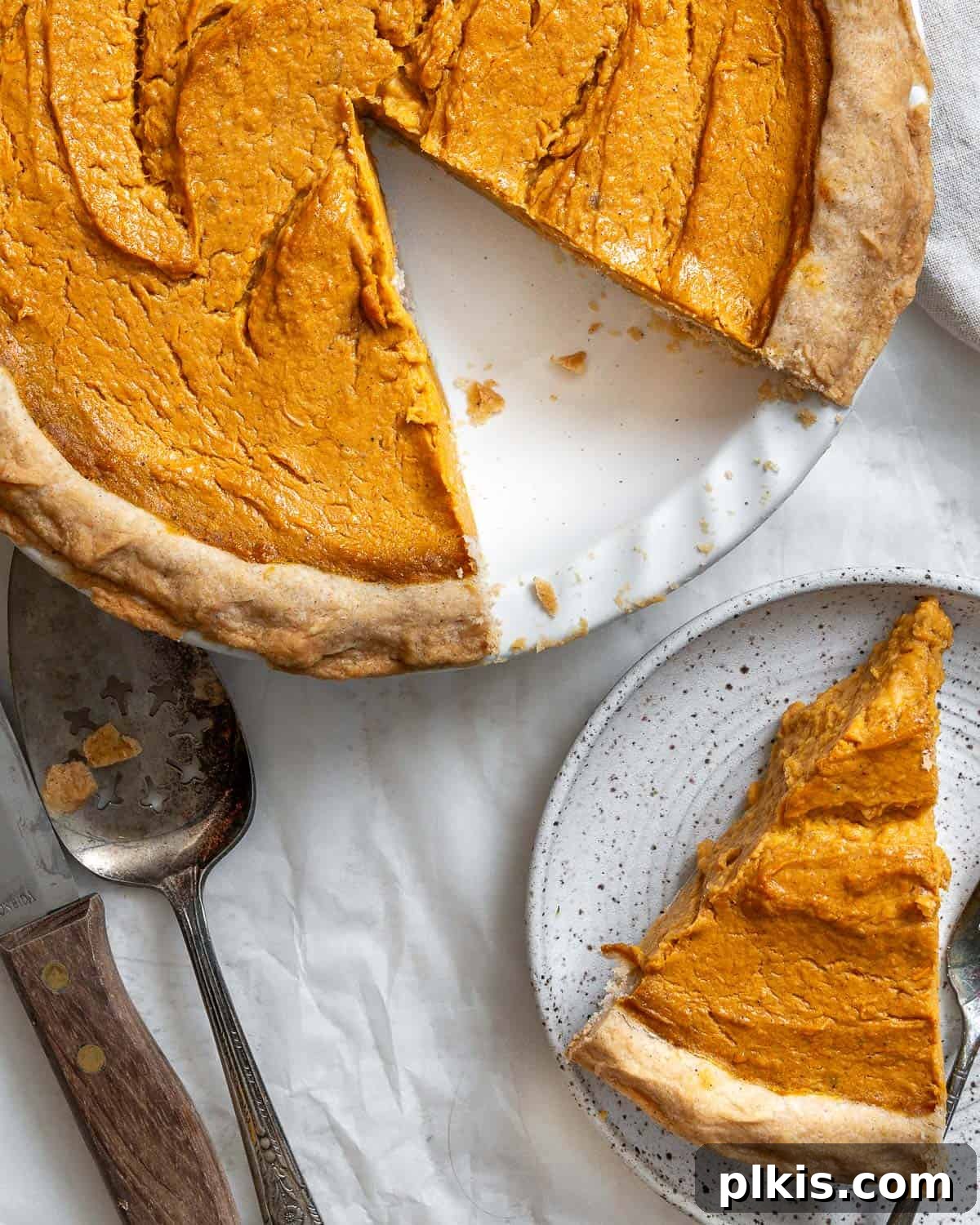 Creamy Vegan Sweet Potato Dream 17 A large, whole Vegan Sweet Potato Pie, perfectly baked and garnished, against a clean white background, inviting a delicious slice.
