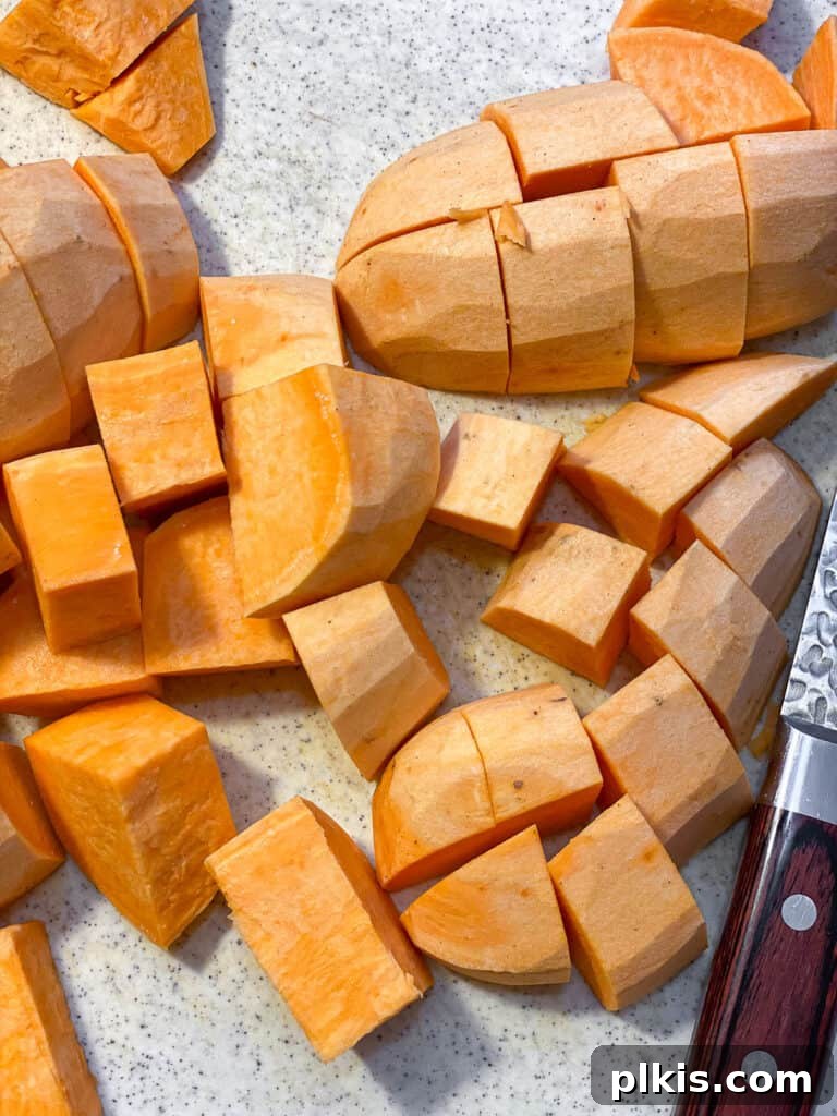 Creamy Vegan Sweet Potato Dream 4 Freshly peeled and cubed sweet potatoes laid out on a white surface, ready for cooking.