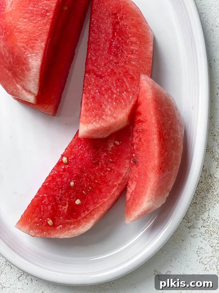 Watermelon Tuna: Sashimi and Steaks 4 Perfectly sliced watermelon, peeled and cut into uniform half-moon pieces, arranged on a white platter, ready for the next step in the vegan tuna preparation.