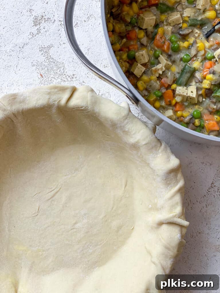 A sheet of puff pastry stretched and fitted into the bottom and sides of an 8x8 inch baking dish, ready to be filled with the creamy vegan pot pie mixture.