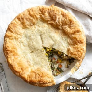 A completed Mixed Vegetable Vegan Pot Pie with a golden-brown flaky crust, ready to be served, set against a pristine white background.