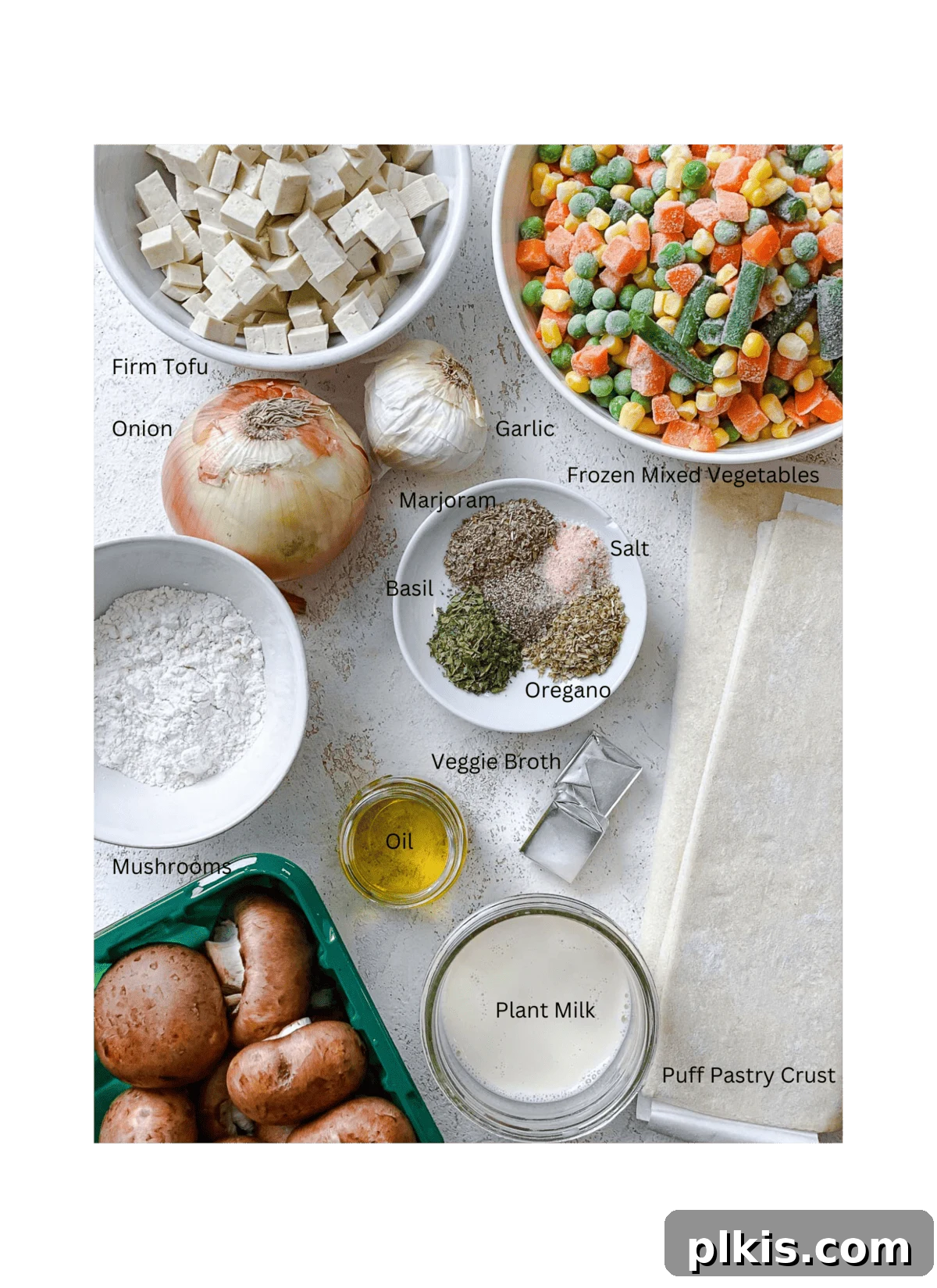 A vibrant display of fresh and frozen ingredients for Mixed Vegetable Vegan Pot Pie, neatly measured out and arranged on a white surface, ready for cooking.