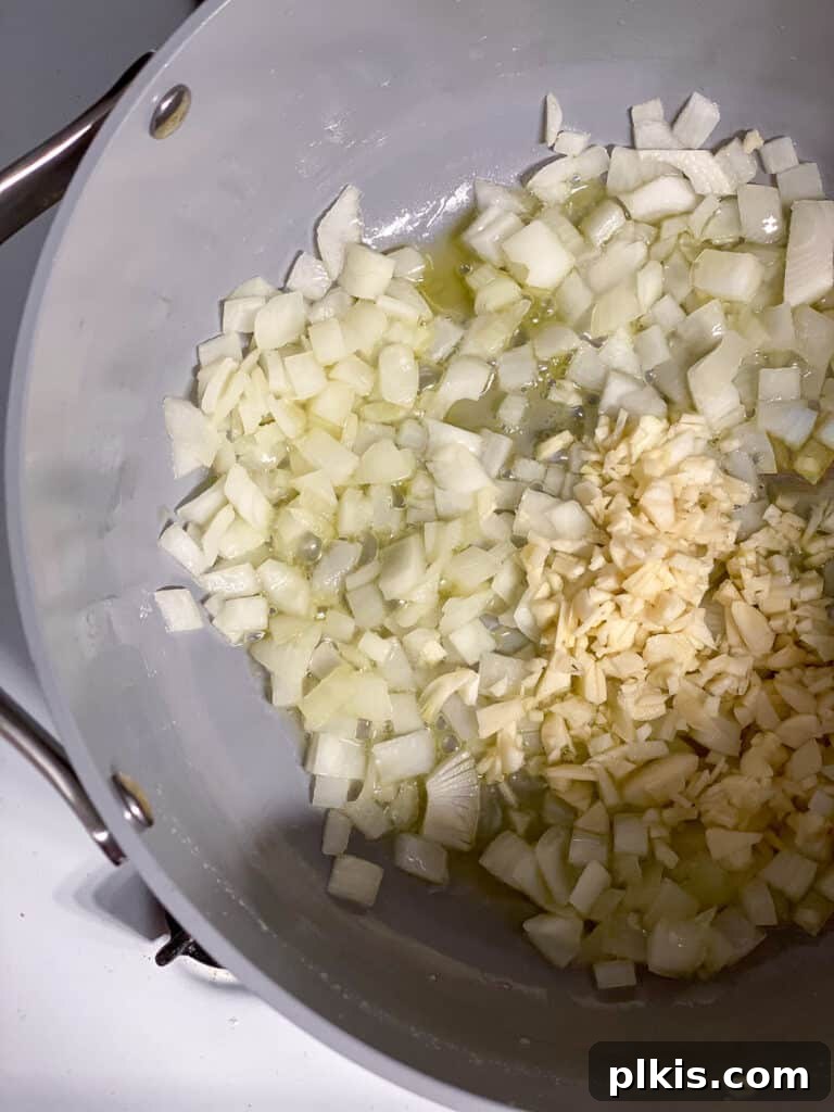 Minced garlic and diced onions sautéing together in a pan, filling the kitchen with a rich, savory aroma, essential for the pot pie's flavor base.