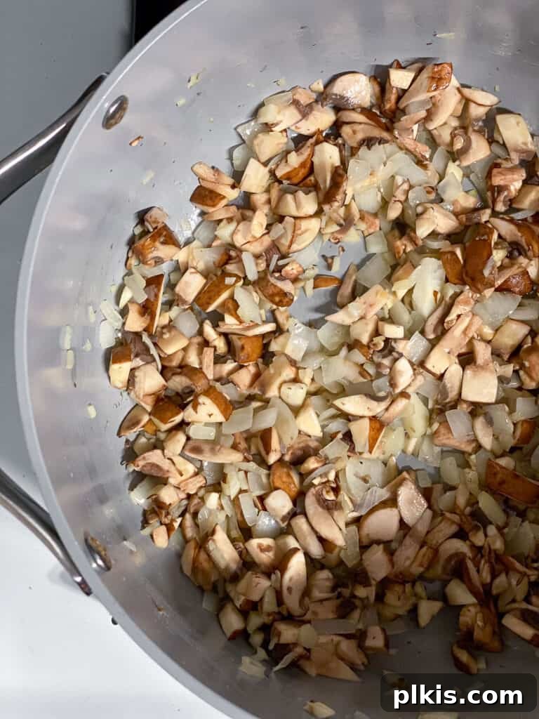 A process shot showing onions, garlic, and mushrooms gently cooking in a pan, forming a flavorful base for the mixed vegetable vegan pot pie.