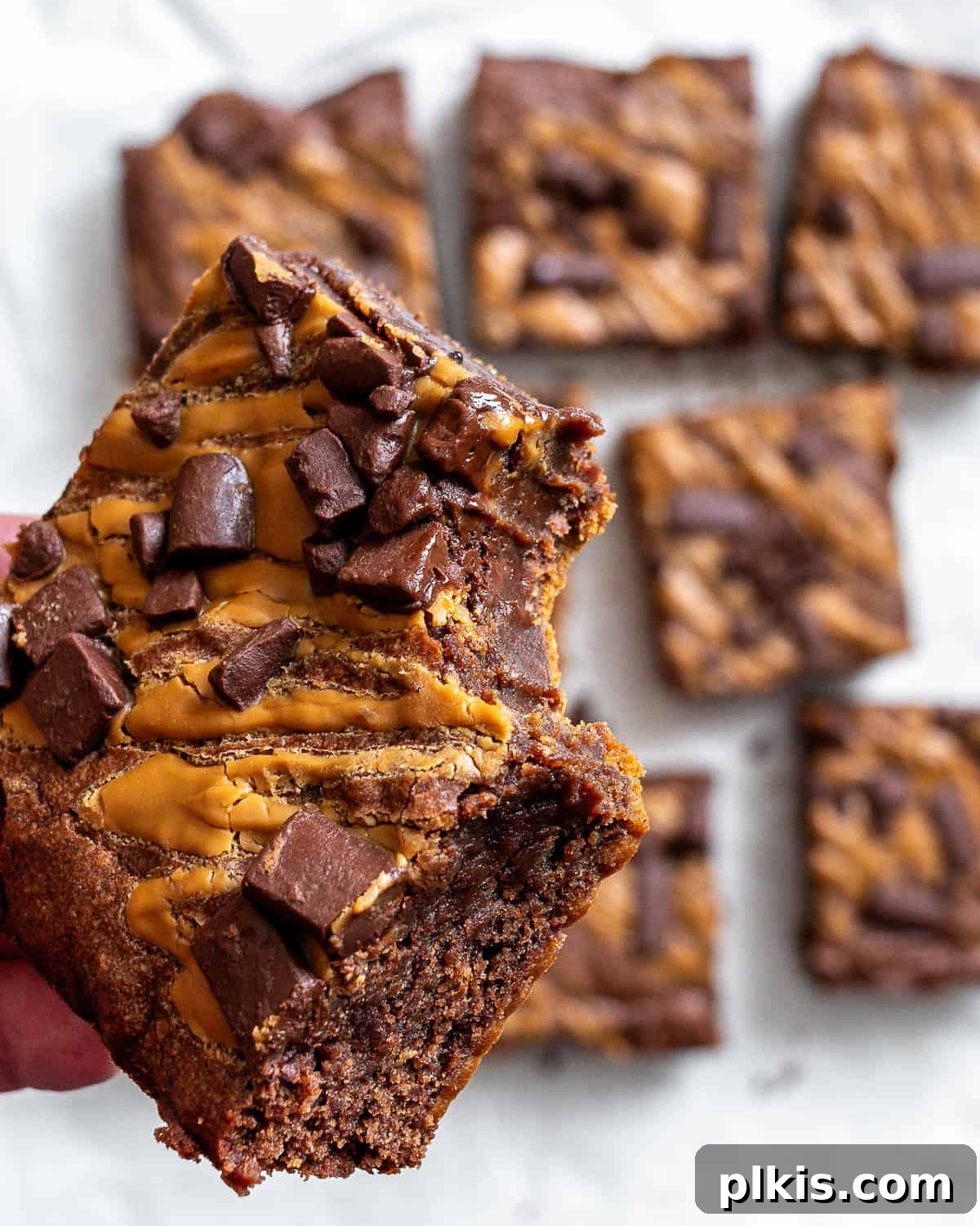 Swirled Biscoff Fudgy Brownies 9 Several Biscoff Brownies artfully arranged on a white surface, highlighting their appealing texture and rich color.