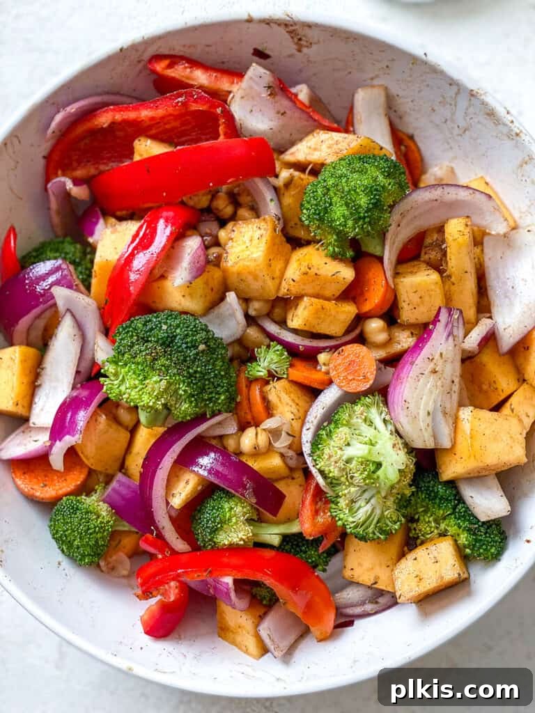 Harvest Roasted Pumpkin Couscous Salad 4 Sliced pumpkin, onions, bell peppers, broccoli florets, and carrots in a mixing bowl, ready for seasoning and roasting.