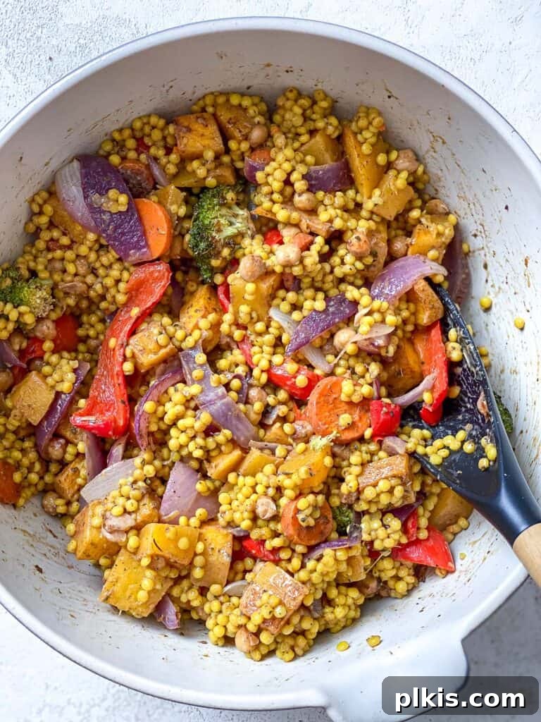 Harvest Roasted Pumpkin Couscous Salad 8 Cooked couscous and roasted vegetables being mixed together in a large salad bowl with a splash of plant-based milk.