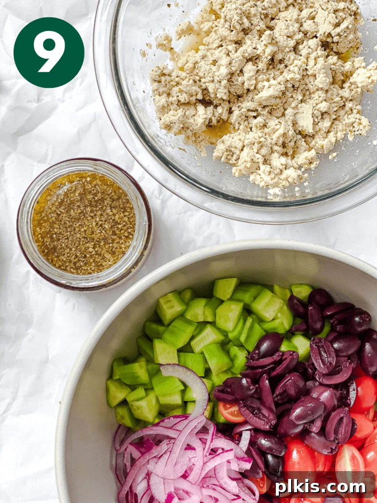 A large bowl showcasing the combined Greek cucumber salad with dressing, topped with crumbled tofu feta, ready to be served.
