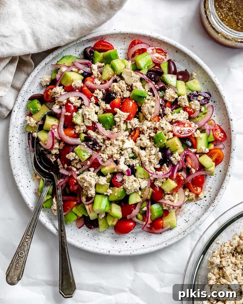 A beautifully plated Greek Cucumber Salad, featuring diced cucumbers, cherry tomatoes, olives, and crumbled vegan feta, artfully arranged and ready to be enjoyed.
