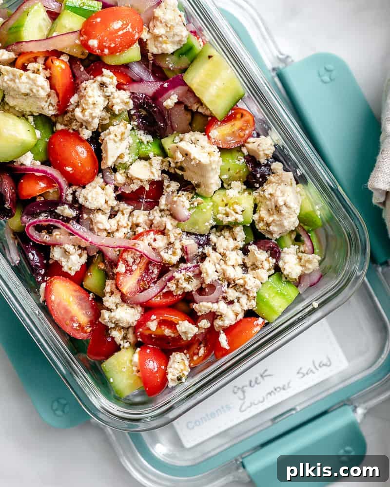 A completed Greek Cucumber Salad stored in a clear airtight container, ready for refrigeration and demonstrating effective meal prep.