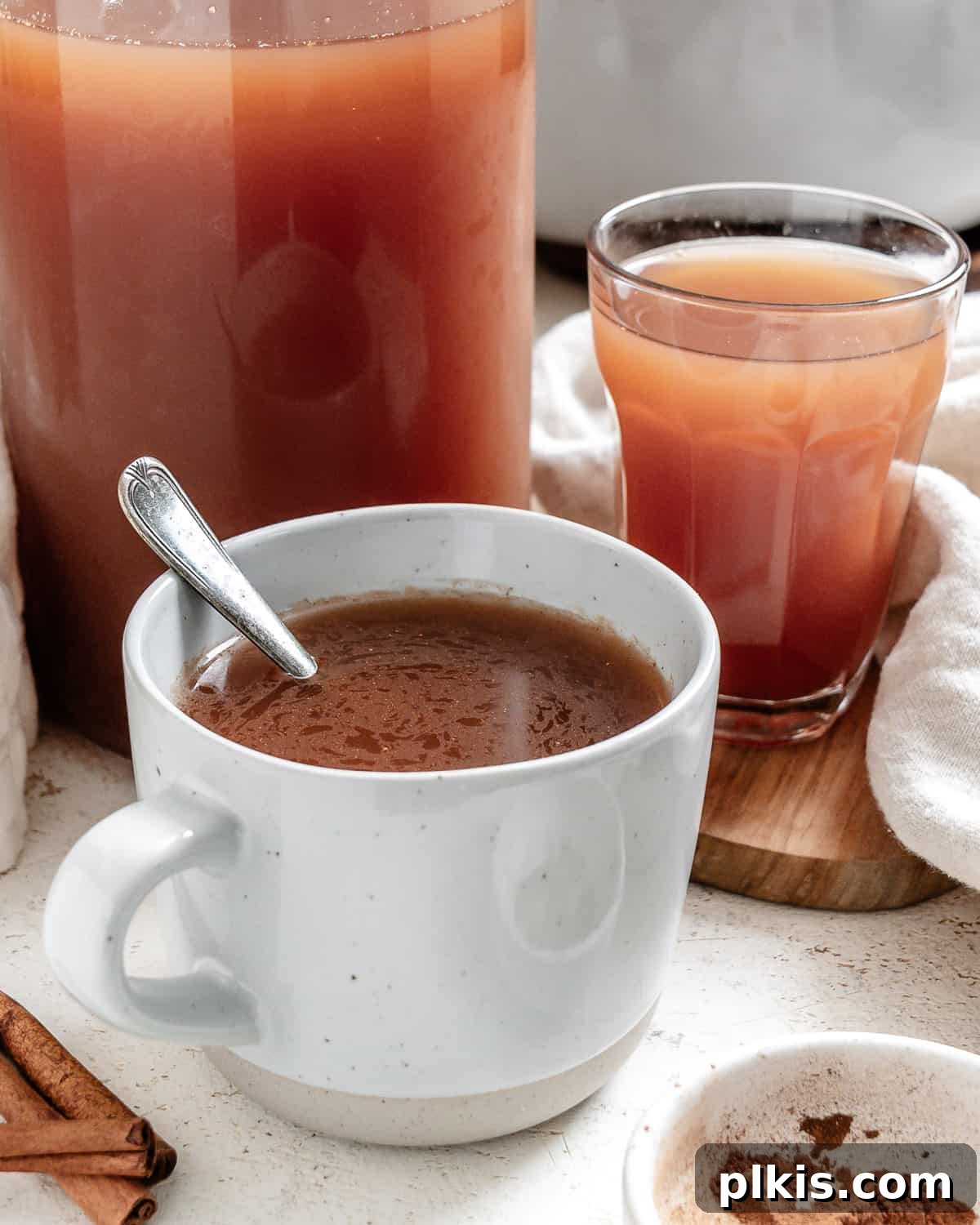 Cozy Spiced Apple Warmer 12 Two cozy cups and a pitcher of completed Mulled Apple Cider, ready to be served.