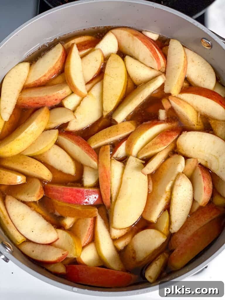 Cozy Spiced Apple Warmer 6 Mixed apples and spices in a bowl, stirred together.