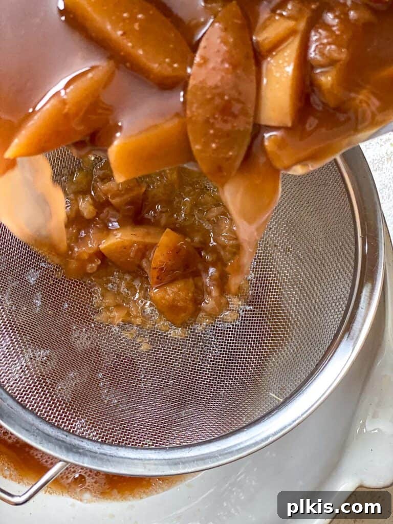 Cozy Spiced Apple Warmer 8 Close-up of apple fiber being pressed above a pot of strained apple mixture.