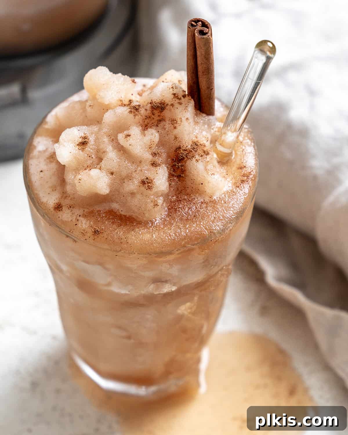 Frozen Apple Cider Delight 2 A glass of perfectly blended apple cider slushie, garnished with an apple slice and a cinnamon stick, capturing the essence of a refreshing fall drink.