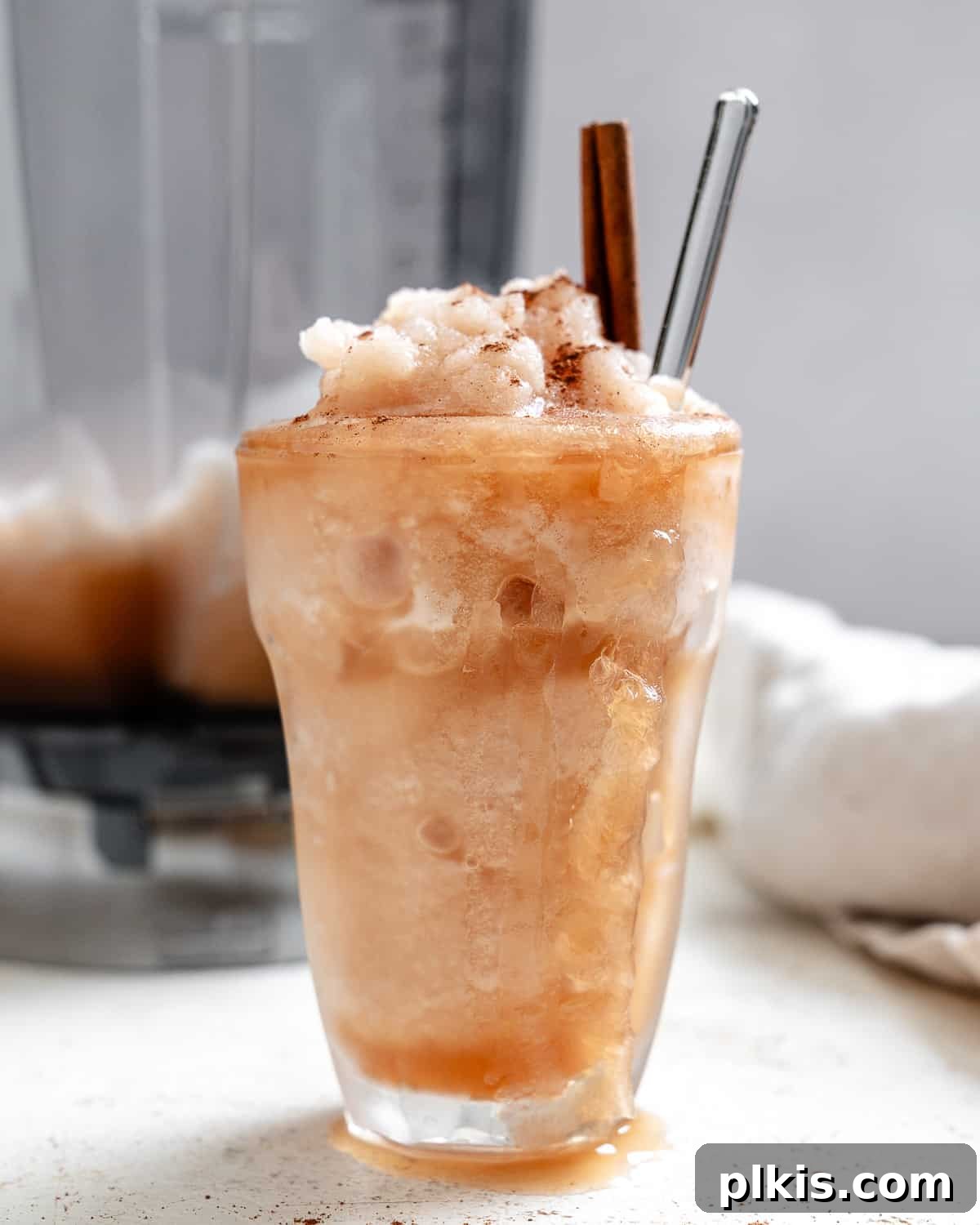 Frozen Apple Cider Delight 7 A beautifully presented spiced apple cider slushie in a glass, garnished with an apple slice and a cinnamon stick, ready to be enjoyed.