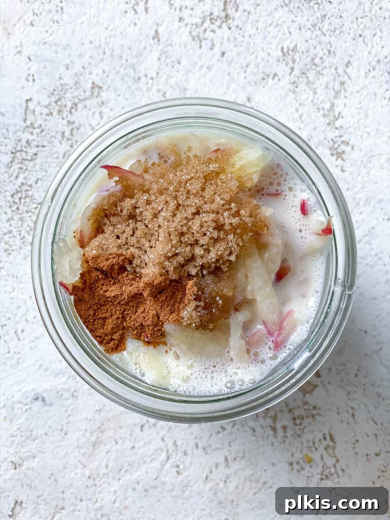 Apple Pie Overnight Oats 5 ingredients added to glass bowl, ready for mixing for Apple Cinnamon Overnight Oats.