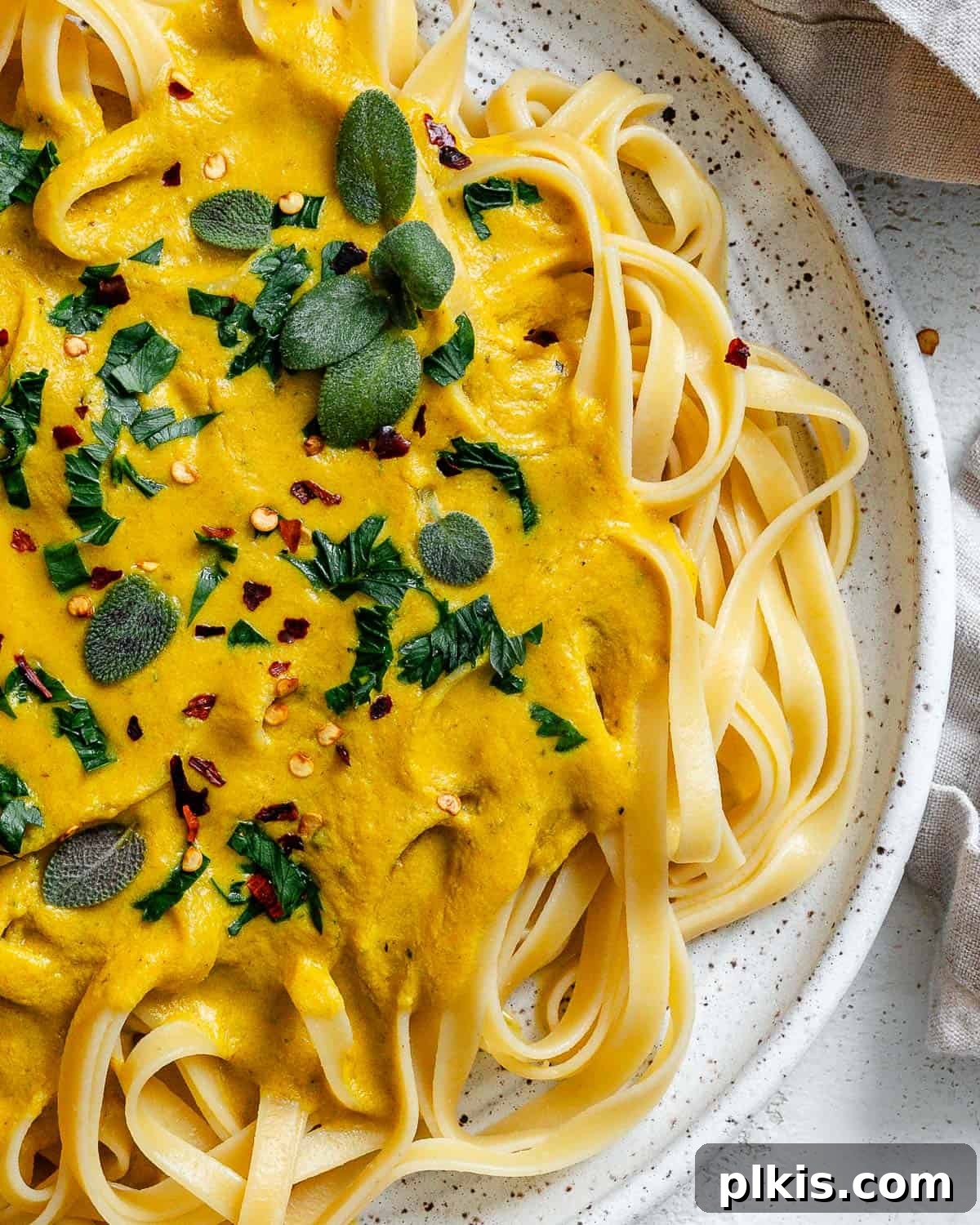 Velvety Pumpkin Pasta 12 completed Creamy Pumpkin Pasta (Vegan) plated on a white plate, close-up with a fork twirled in the pasta