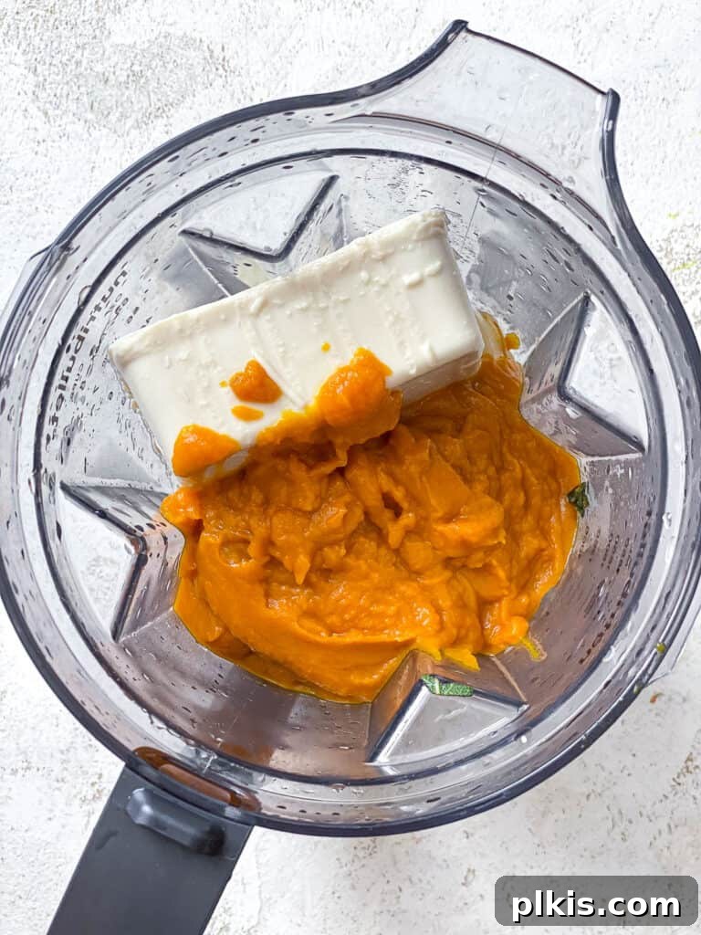 Velvety Pumpkin Pasta 8 process shot showing silken tofu and pumpkin puree added to the blender with aromatics
