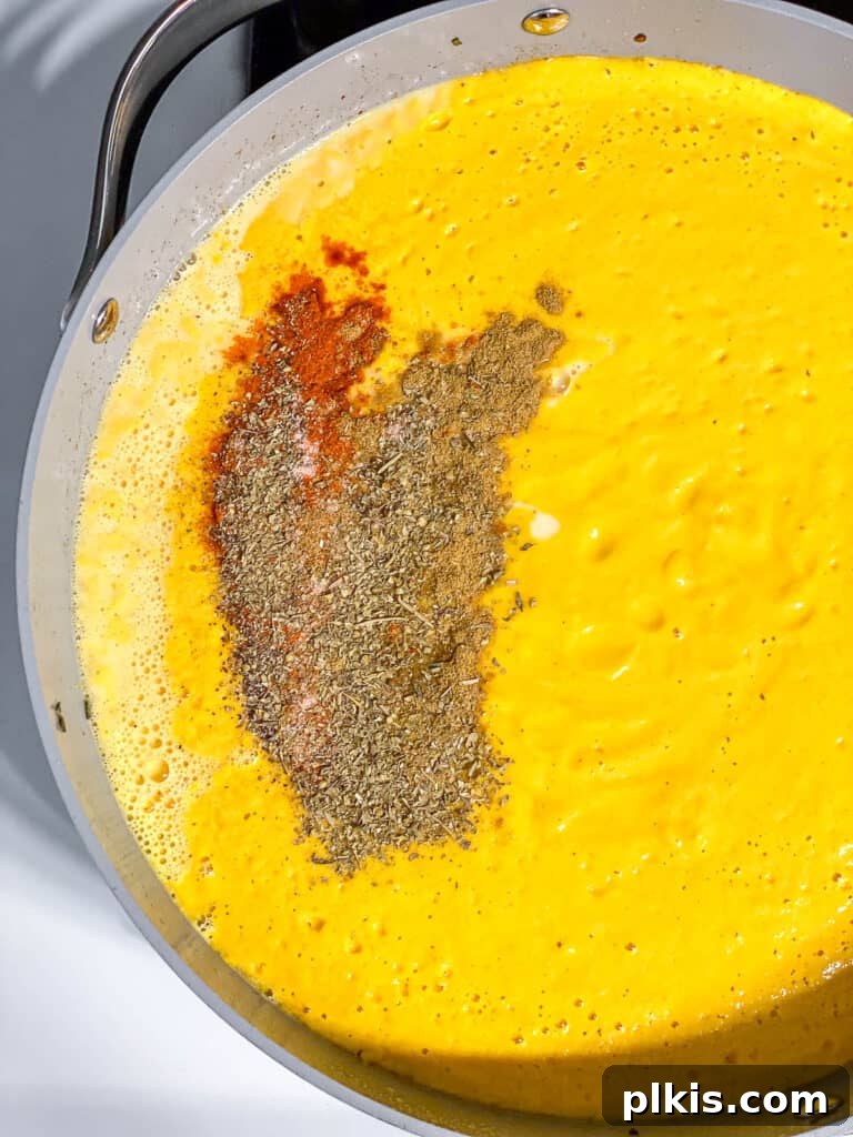 Velvety Pumpkin Pasta 10 process shot showing various spices added to the simmering pumpkin sauce in the pot
