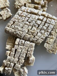 process of cutting tempeh into small cubes against a white background