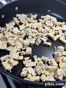 process of cooking tempeh pieces on a black griddle, starting to brown