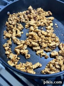 process of browned, flavored tempeh cooking on a black griddle, sauce simmering