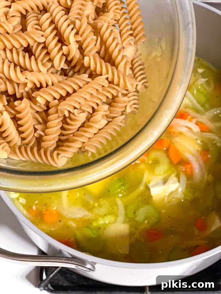 Vegan Chicken Noodle Soup: Stovetop, Instant Pot, and Slow Cooker 11 process shot of adding pasta to soup