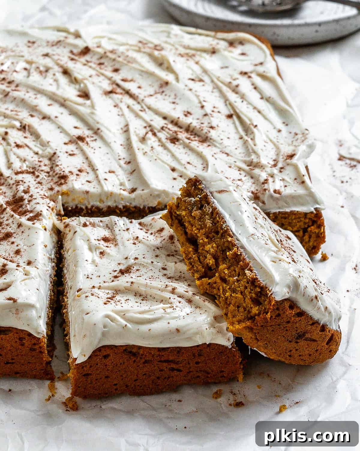 Vegan Pumpkin Delight 2 A beautifully frosted and sliced Vegan Pumpkin Cake on a white surface, ready to be enjoyed.