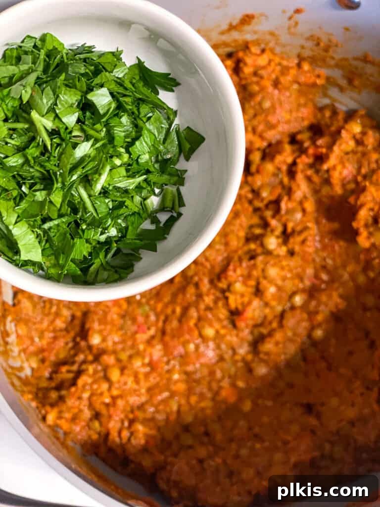Hearty Lentil Sloppy Joes for Stove Top or Slow Cooker 16 Process shot of fresh parsley being added to the lentil sloppy joe mixture.