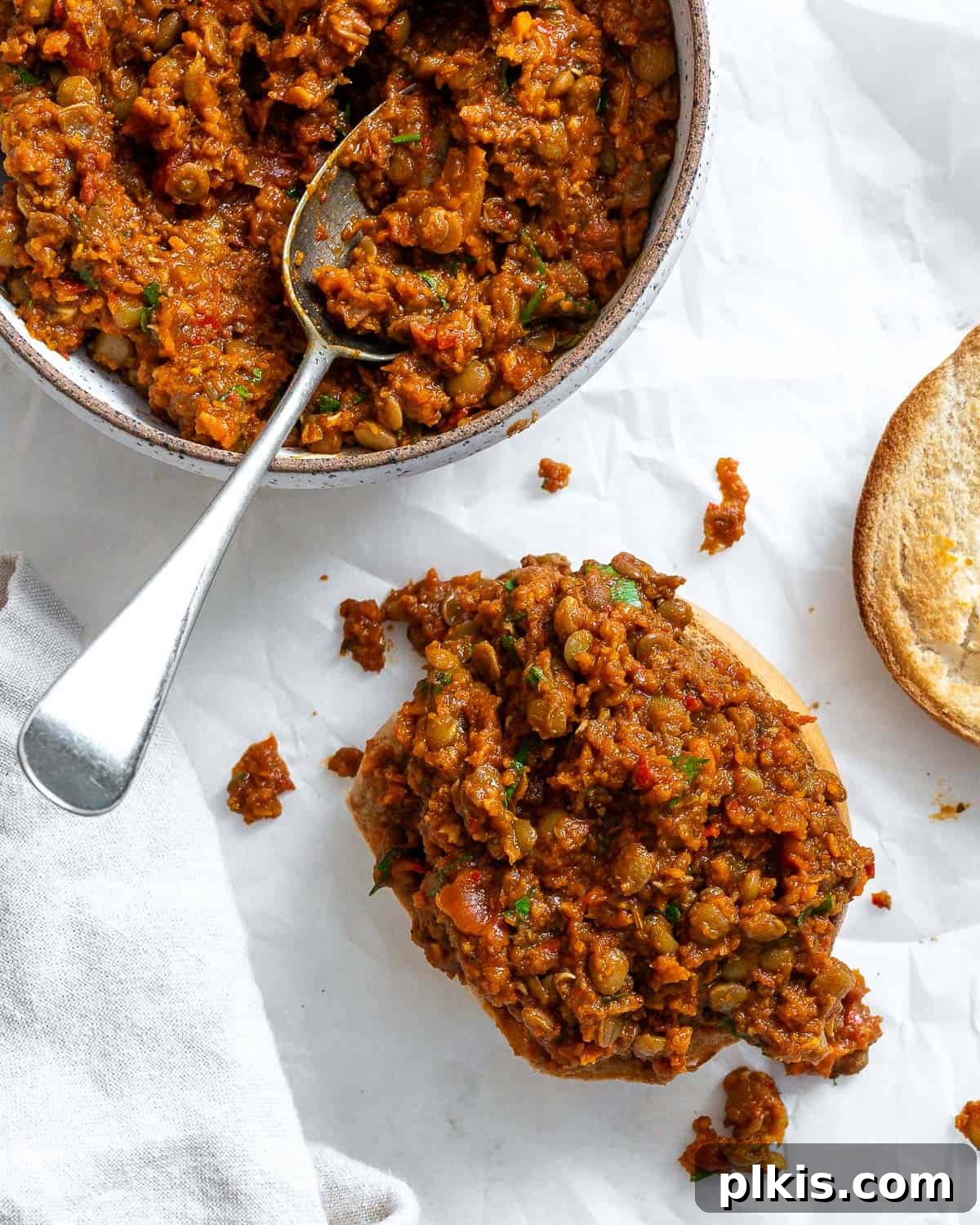 Hearty Lentil Sloppy Joes for Stove Top or Slow Cooker 18 Completed Lentil Sloppy Joes served in a bowl and on a hamburger bun, garnished with fresh herbs.