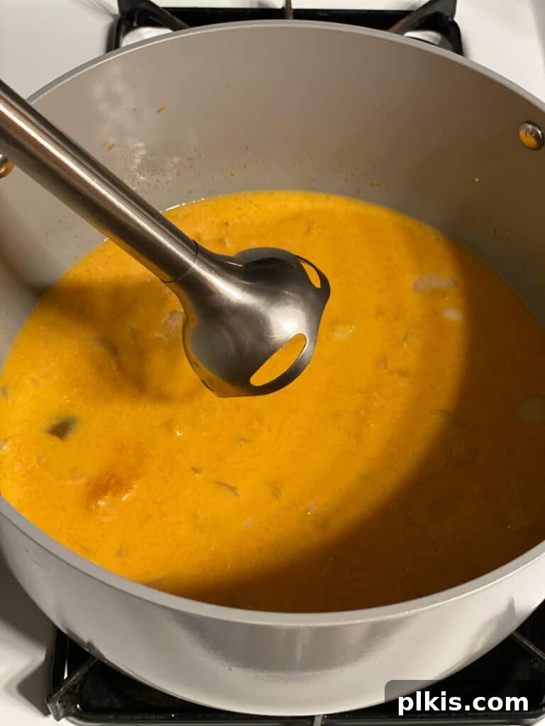Golden Thai Squash Elixir 17 An immersion blender actively pureeing the soup directly in the pot until smooth and creamy.