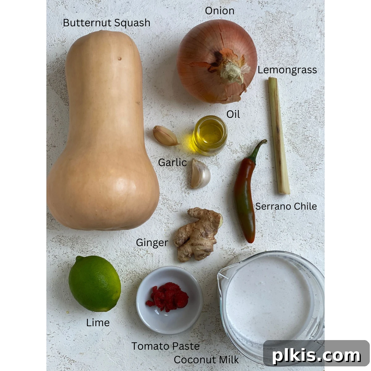 Golden Thai Squash Elixir 3 All the fresh ingredients for Thai Style Butternut Squash Soup, including a whole butternut squash, coconut milk, fresh ginger, garlic, lime, and chiles, neatly arranged on a white surface, ready for preparation.