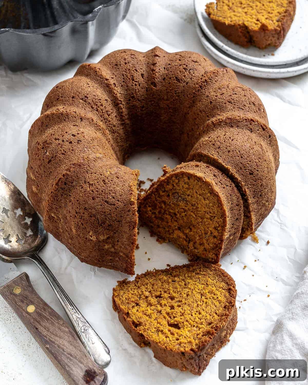 A beautifully completed Easy Vegan Pumpkin Bundt Cake on a pristine white surface, drizzled with a rich spiced glaze. Perfect for fall celebrations and plant-based indulgence.