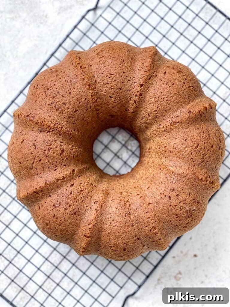 A freshly baked Easy Vegan Pumpkin Bundt Cake cooling completely on a wire rack after being inverted from the pan, ready for glazing.