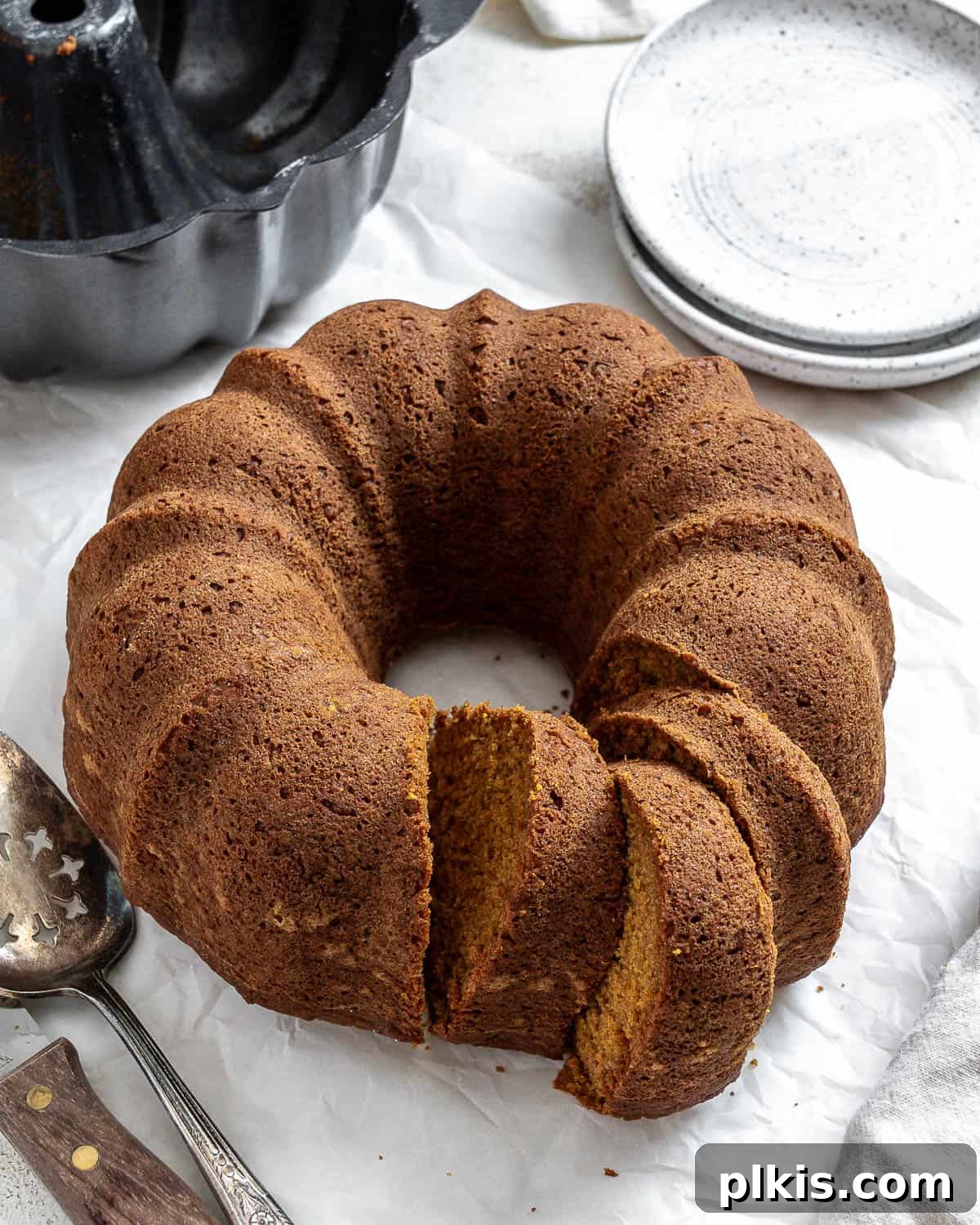 A stunning, fully glazed Easy Vegan Pumpkin Bundt Cake presented elegantly on a white surface, showcasing its perfect shape and inviting texture.
