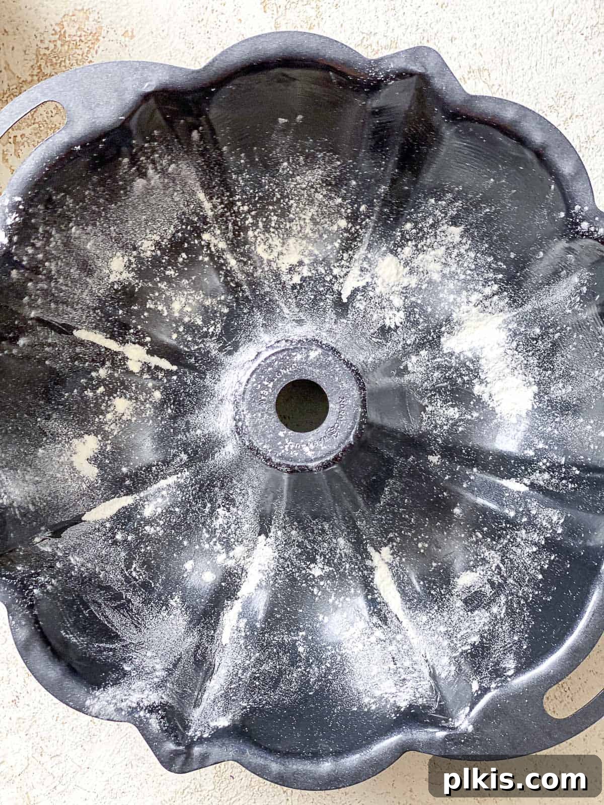 A bundt pan lightly dusted with flour after being greased with vegan butter, preparing it for the cake batter and ensuring an easy release.