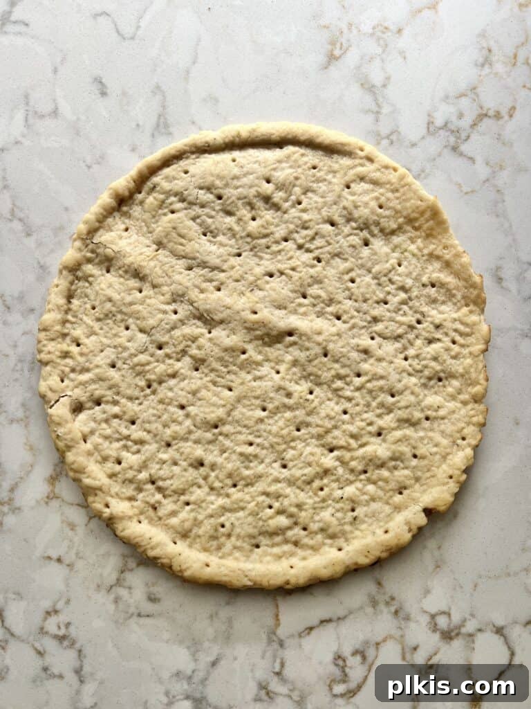 Plant-Powered BBQ Pizza 4 A single pizza crust is laid out on a clean white marble surface, ready for the toppings to be added, signaling the beginning of the pizza assembly process.