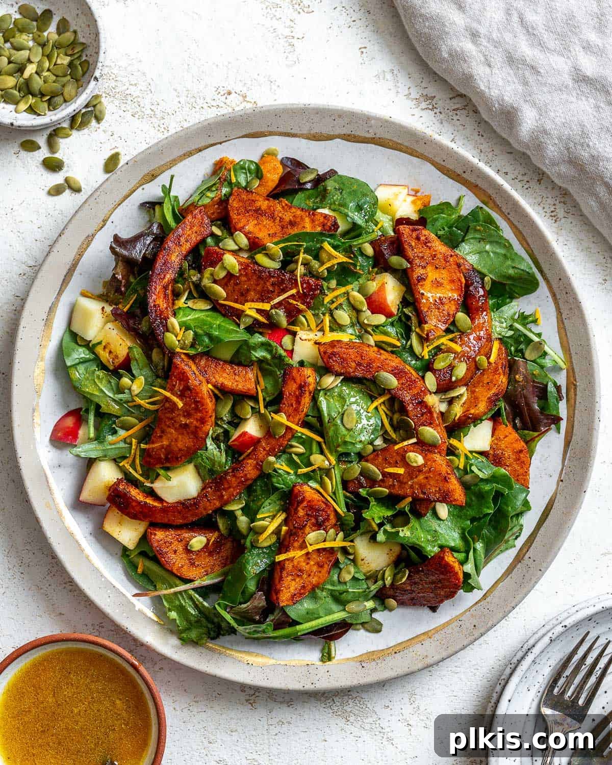 A beautifully presented Easy Butternut Squash Salad on a clean white surface, showcasing roasted squash, apple, and pepitas.