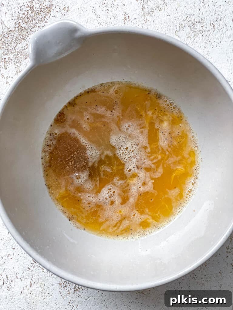 Process shot showing the vibrant orange dressing mixed together in a small bowl, ready for the Easy Butternut Squash Salad.