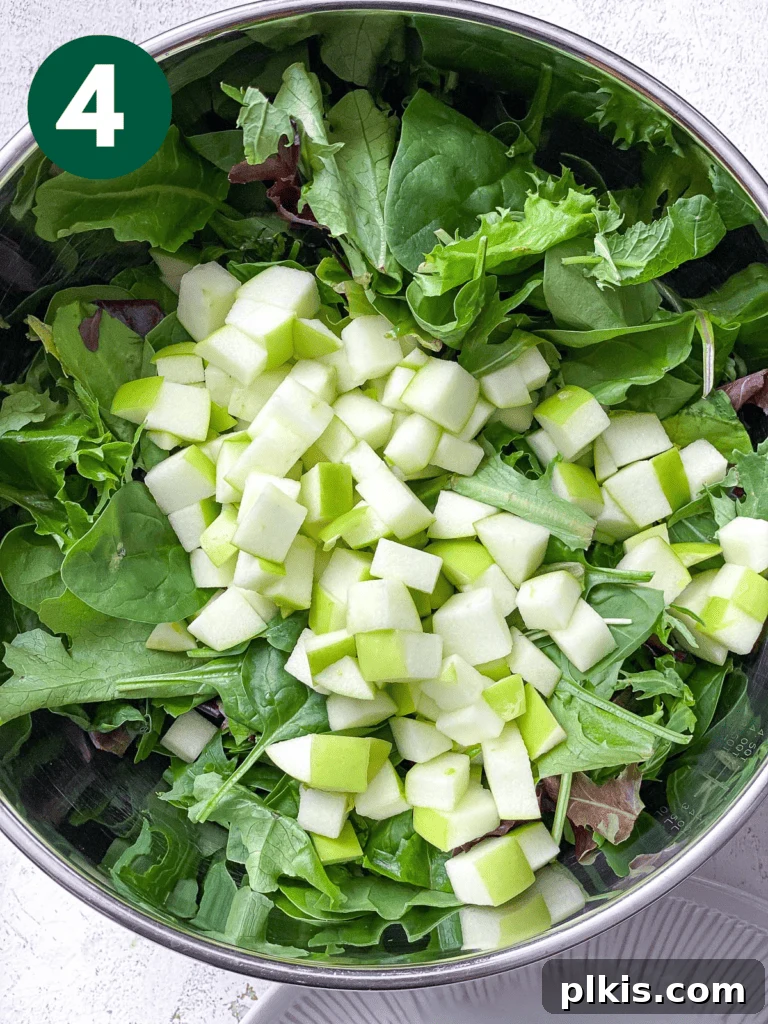 Crisp Apple Pecan Cranberry Salad 7 Process shot of adding fresh salad ingredients to a large bowl.