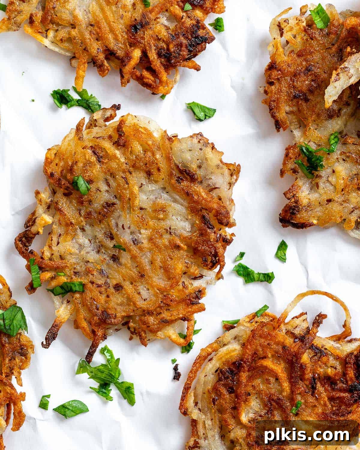 Crispy Vegan Potato Latkes 2 Completed Vegan Potato Latkes arranged artfully on a white surface, garnished with fresh herbs, showcasing their golden-brown crispiness and inviting texture.